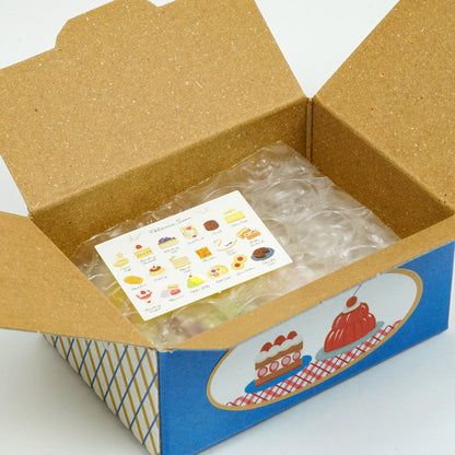 Open cardboard box with a blue border containing a sheet of stickers on a white background